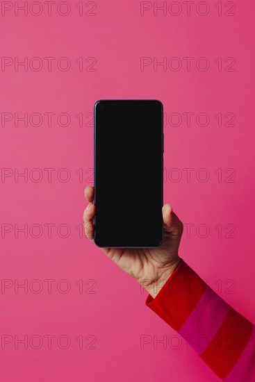 Crop anonymous person in casual clothes showing modern smartphone with empty screen while standing on pink background