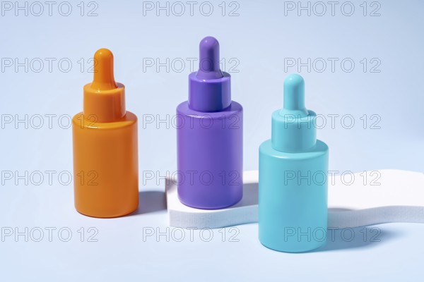 Three serum bottles in vibrant orange, purple, and turquoise colors, showcased against a soft blue background, demonstrating modern cosmetic packaging