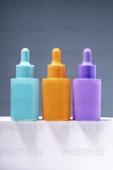 Three vibrant and colorful serum bottles aligned on a sleek surface with a soft gray gradient background, emphasizing modern aesthetics in skincare packaging