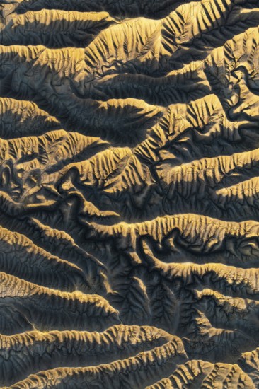 Capturing the intricate golden textures of Caineville Mesa, Utah, this aerial view reveals the stunning patterns and ridges formed by natural erosion in a desert landscape