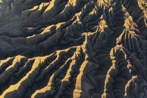 Aerial view of Caineville Mesa in Utah, showcasing the stunning textures and patterns of desert landscapes bathed in golden sunlight. Rugged terrain and natural beauty
