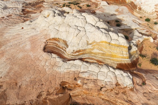 Aerial view of sandstone formations showcasing layered textures and vibrant colors in White Pocket. Unique patterns and natural erosion highlight the beauty of desert geology in Arizona, USA