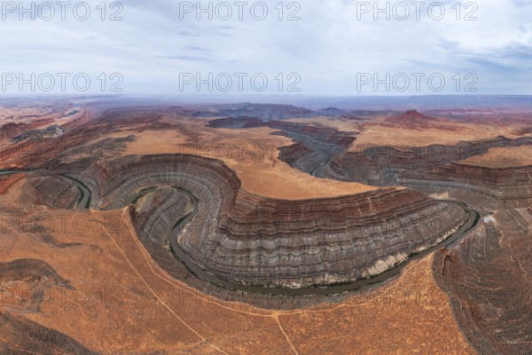 Panoramic aerial view of the San Juan canyon, showcasing the rich geological formations created by a winding river cutting through the arid landscape of Utah desert terrain in USA