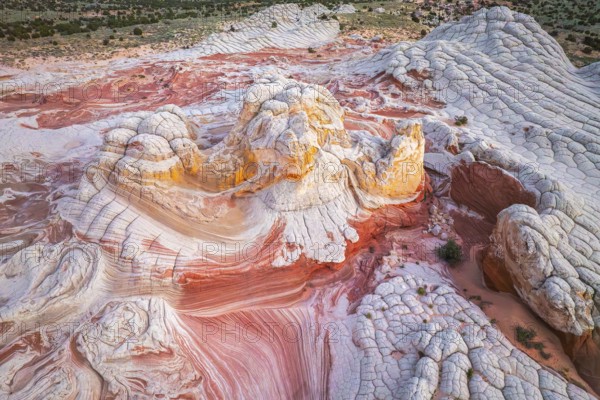 Aerial view of swirling rock formations in vibrant reds and whites in White Pocket, showcasing the intricate patterns and textures created by natural erosion in a desert landscape in Arizona, USA