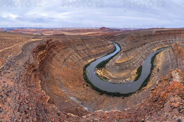 Aerial view of a winding river carving through layers of ancient rock formations in a desert San Juan canyon landscape, showcasing the beauty of natural erosion and stunning geology in Utah, USA