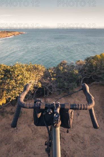 Experience a serene cycling journey along the coastal trails of Zahara de los Atunes, Cadiz. This image captures a cyclist's perspective overlooking the scenic blue waters