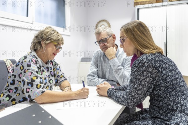 A couple with intellectual disabilities engaged in a focused supervision meeting. They are discussing documents, communication, and collaboration in a professional environment