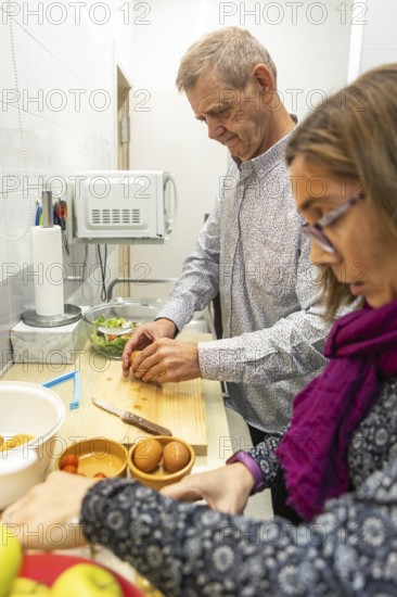 A couple with intellectual disabilities prepares a healthy meal in a cozy kitchen of the supervised home. They chop vegetables and organize ingredients on a wooden cutting board