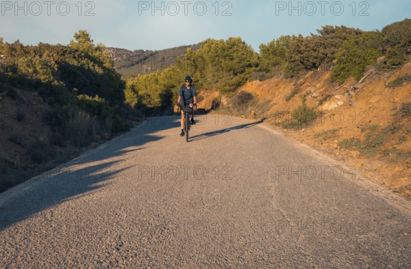 Male cyclist descending a lush mountain road, located in Zahara de los Atunes, Cadiz, capturing the essence of outdoor adventure in a warm, tranquil setting