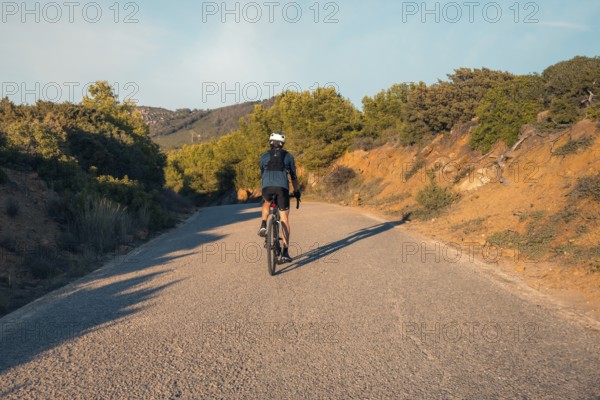 Back view of an unrecognizable male cyclist riding on a quiet road through the hills near Faro Camarinal, Zahara de los Atunes, Cadiz
