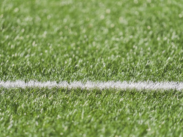 A close up image showcasing the lush green grass of a soccer field with a crisp white line marking. The vibrant texture highlights the field well maintained condition