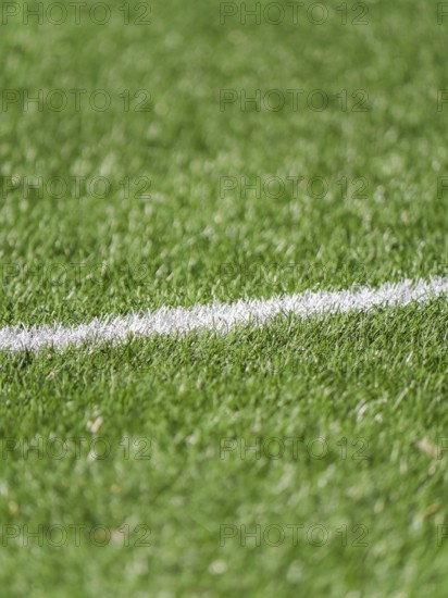 A close up image of a lush green grass soccer field featuring a white boundary line. The vibrant texture and clear marking highlight athletic grounds like soccer or football fields