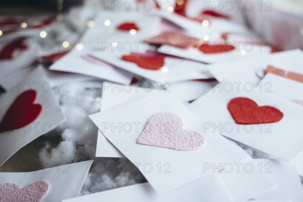 A collection of handmade Valentine's Day cards with red hearts on white envelopes, scattered decoratively. Perfect for expressing love and affection