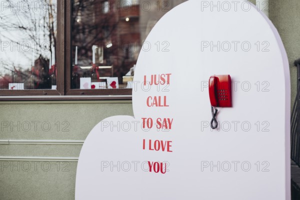A Valentine's Day display featuring a red phone and the message I just call to say I love you, set against a heart-shaped background near a window store