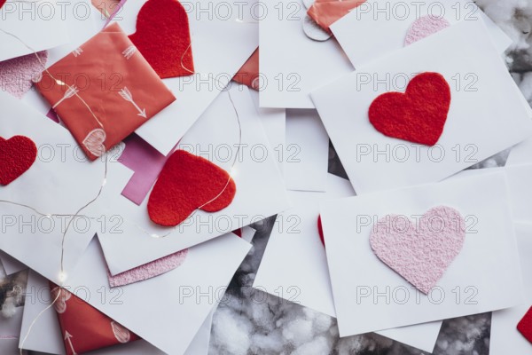 Valentine's Day envelopes adorned with red and pink felt hearts, scattered elegantly among fairy lights. A perfect scene capturing love and affection