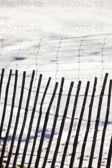 A rustic wooden fence stands in contrast against a serene snowy backdrop, showcasing a blend of natural textures and simplicity in a tranquil winter setting