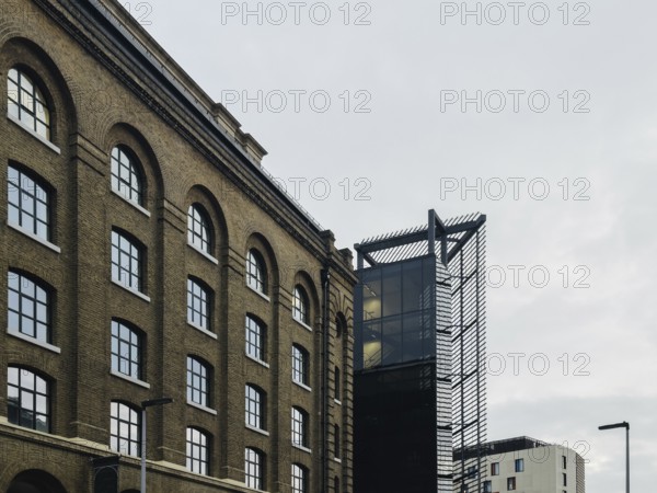 A striking juxtaposition of historic brick architecture with modern glass and steel structures in a London street. The image highlights urban diversity and architectural evolution