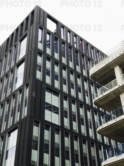 A striking modern building in London showcasing sleek lines and geometric patterns against a clear sky. The contrasting materials highlight urban design innovation