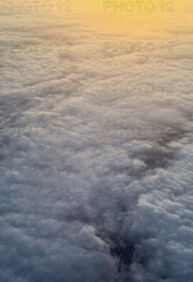 Captured from above, this image showcases a stunning blanket of fluffy clouds illuminated by a warm sunrise, creating a tranquil and breathtaking scene over London