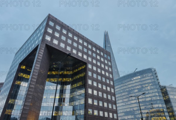 A striking view of London's modern architecture at dusk, featuring towering skyscrapers with illuminated windows against the evening sky, showcasing urban design and innovation