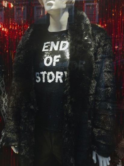 A fashionable mannequin in a London storefront displays a black faux fur coat and a sparkling sequin shirt with the phrase End of Story, set against a red background