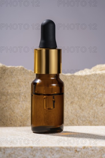 A stylish amber glass serum bottle with a black dropper and golden details, showcased on a textured stone podium, ideal for luxury skincare branding