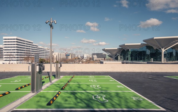 A newly constructed transport hub in Valdebebas, Madrid, featuring a sleek glass facade and modern design. Facilities for metro, underground, suburban trains, and buses. Equipped with a spacious green parking area for electric vehicles