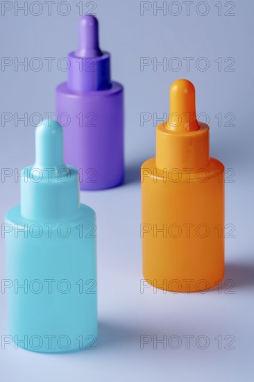 A trio of vividly colored serum bottles in purple, orange, and teal, arranged aesthetically against a light gray background