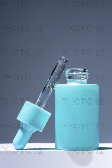 A striking image featuring a turquoise serum bottle with a glass dropper filled with liquid, set against a contrasting gray background