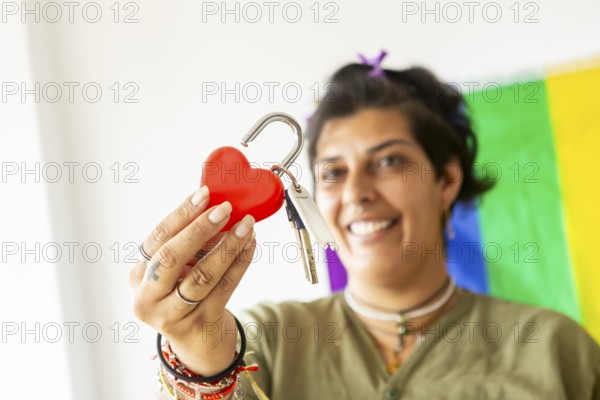 A joyful transgender woman holds keys and a heart lock, symbolizing a new beginning in her home. A pride flag in the background celebrates LGBTQIA+ identity and love