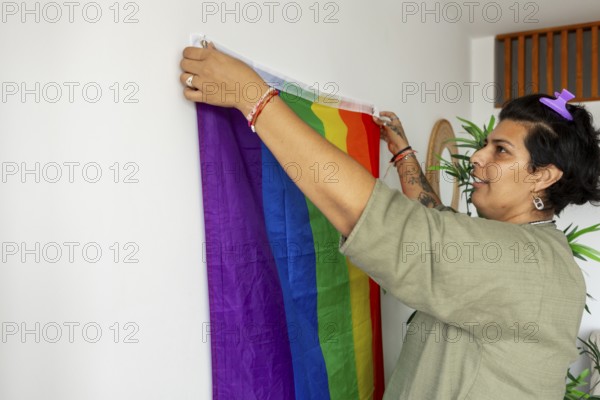 A trans woman joyfully decorating her new home with a rainbow pride flag, symbolizing LGBTQIA+ pride and personal freedom. The setting reflects a welcoming and inclusive atmosphere