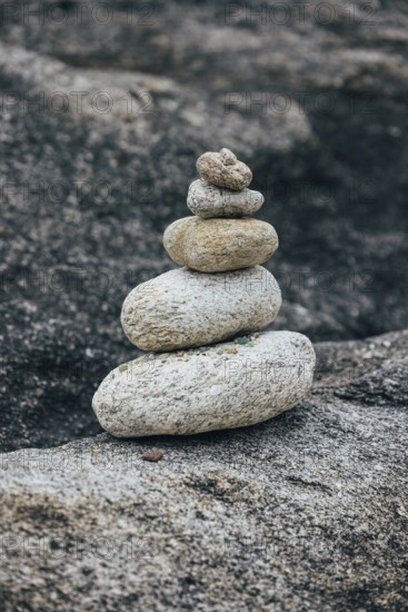 A stack of balanced stones sits on a rocky surface in a peaceful outdoor environment. The image conveys themes of balance, meditation, and tranquility. Perfect for nature, zen, and mindfulness topics