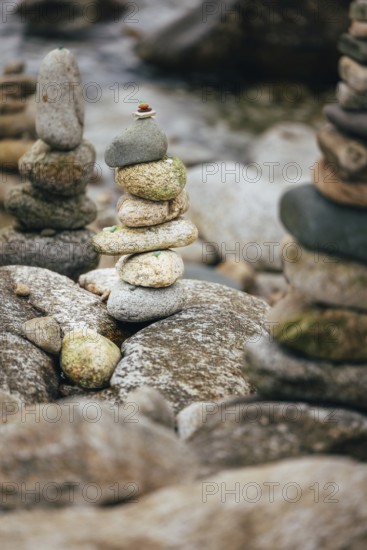 A stack of balanced stones on a rocky surface in a peaceful outdoor setting besides the sea. Concept of balance, meditation, and tranquility for nature, zen, and mindfulness topics
