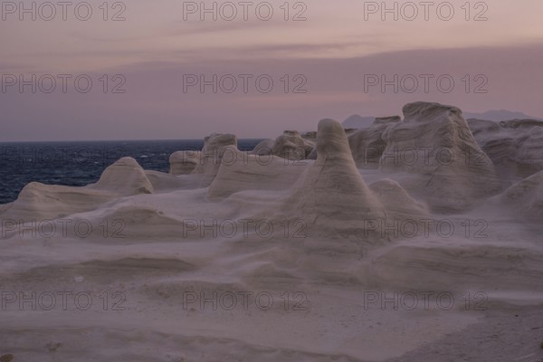 Serene evening view of the distinctive white rock formations at Sarakiniko Beach on the island of Milos, Greece, under a pastel sky