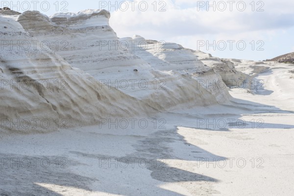 Striking, natural white rock formations at Sarakiniko Beach on the island of Milos, Greece. The smooth, sculptural cliffs and textured sand create a dramatic landscape