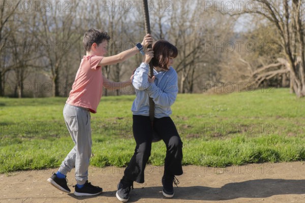 Two friends enjoy a sunny day at the park, playing on a zip line with grassy scenery. The joy of childhood and outdoor play captures the spirit of adventure and friendship