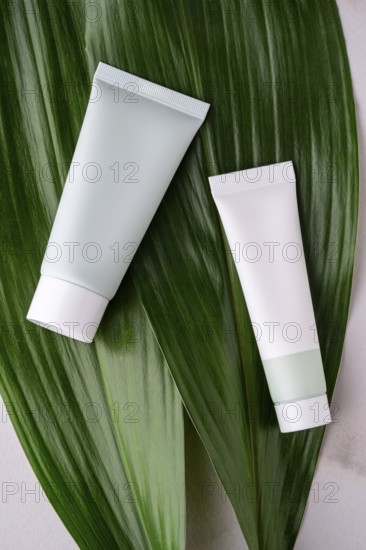Two white cosmetic tubes lay elegantly on a large, vibrant green leaf, symbolizing natural and eco-friendly skincare solutions