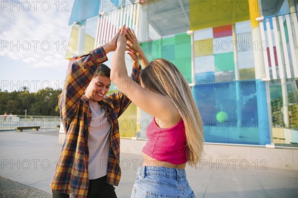 A happy lesbian couple dances joyfully in a vibrant outdoor setting, celebrating love and diversity. Their smiles radiate positivity, reflecting an inclusive and equal relationship