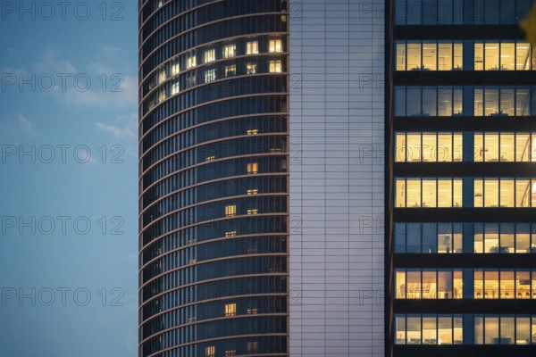 An urban skyscraper's windows glow warmly against the fading evening sky, capturing the essence of city commuting life and architectural beauty in the downtown hustle