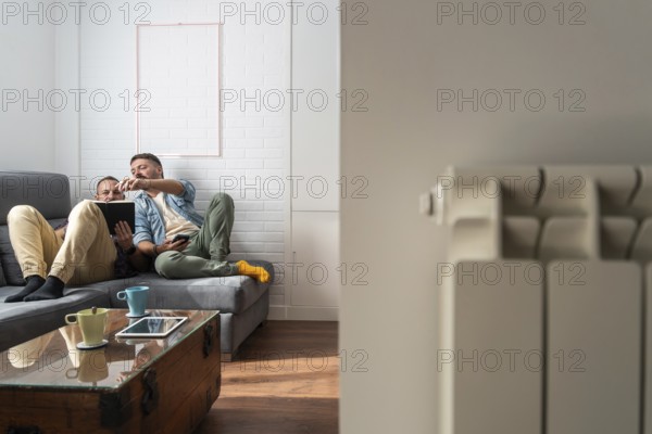 A gay couple enjoying a relaxing day at home, sitting on a comfortable sofa while engaging with book, surrounded by warm and inviting home decor