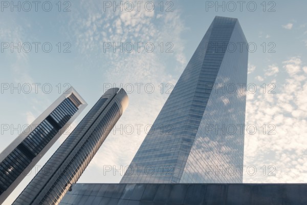 A low-angle view of modern skyscrapers against a cloud-dotted sky in an urban setting. The image highlights contemporary architecture and city life, ideal for commuting and business themes