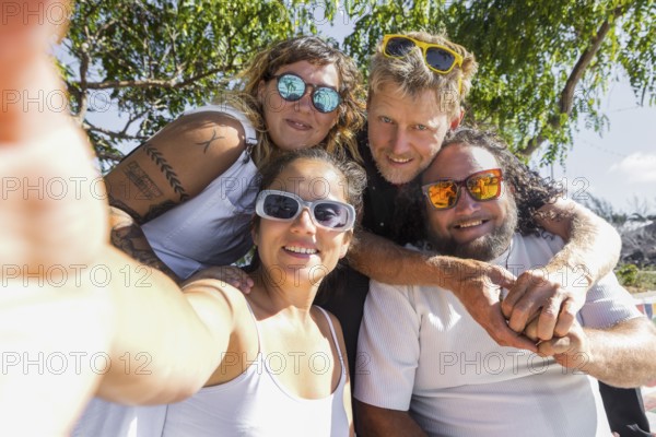 A cheerful group of LGBTQIA+ couples enjoying a sunny day outdoors. Their happy expressions and close poses convey unity, pride, and love in a natural setting
