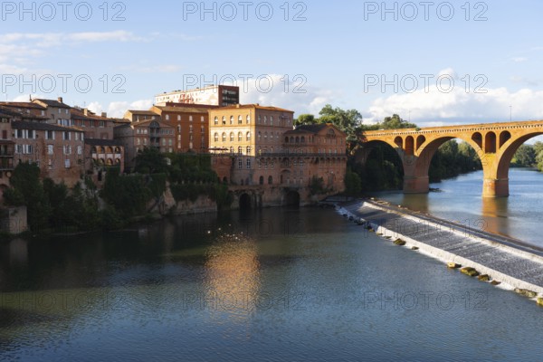 A stunning view of Albi, a historic town in southern France The picturesque riverfront features terracotta buildings, a charming arched bridge, and reflections in the calm waters