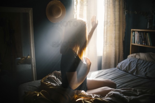 A woman sits on a bed, bathed in morning sunlight streaming through the window. The warm glow illuminates the room, creating a peaceful and serene atmosphere