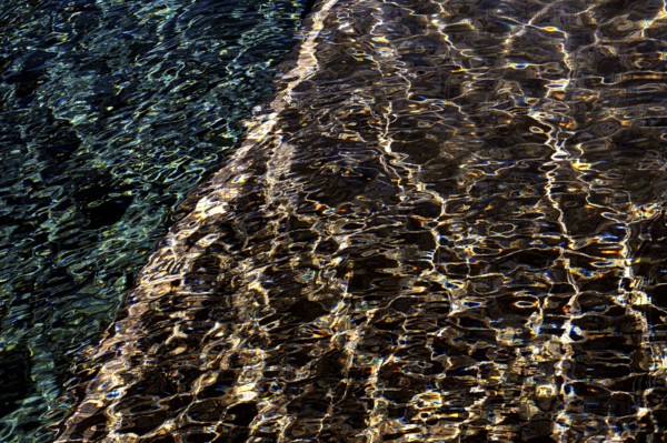 Abstract ripples on the water surface captured at Playa Blanca Port in Lanzarote, illustrating a mesmerizing play of light and shadow