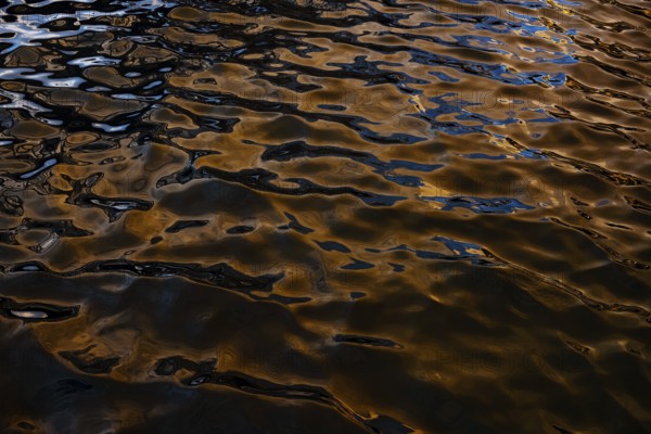 Captivating golden reflections dance on the rippling waters at Playa Blanca Port in Lanzarote, creating a mesmerizing texture and vibrant color play ideal for artistic imagery