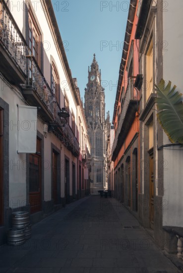 A serene cobblestone street leading to the iconic San Juan Bautista Church in Arucas, Gran Canaria, framed by traditional architecture and clear skies