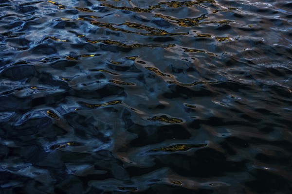 Dark and moody water textures captured at Playa Blanca Port in Lanzarote. Intricate light reflections and patterns grace the fluid landscape, emphasizing the serenity and mystery of this unique location