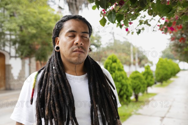 A man with long dreadlocks stands peacefully with his eyes closed under blooming bougainvillea Located in the charming streets of Barranco, Lima, Peru