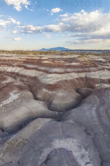 Striking aerial photograph capturing the multi-colored, layered bentonite hills in the rugged landscapes of Utah, showcasing a unique geological formation under a clear blue sky